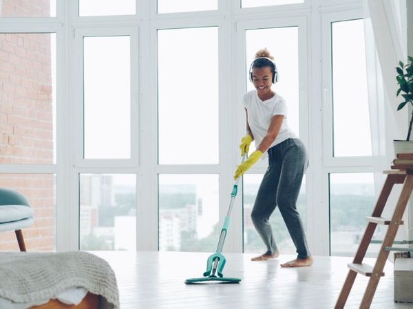 Woman in a white t-shirt mopping a bright living room floor