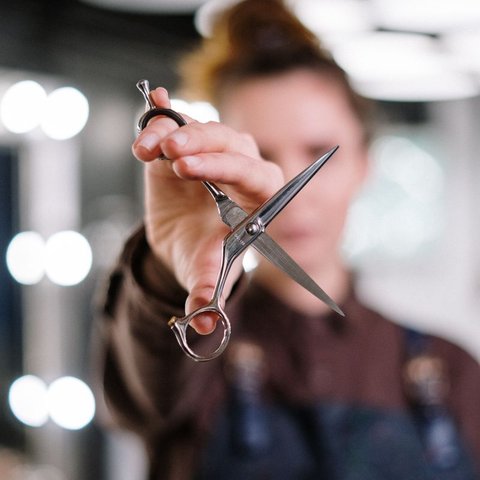 Hair stylist in an apron holding up professional scissors