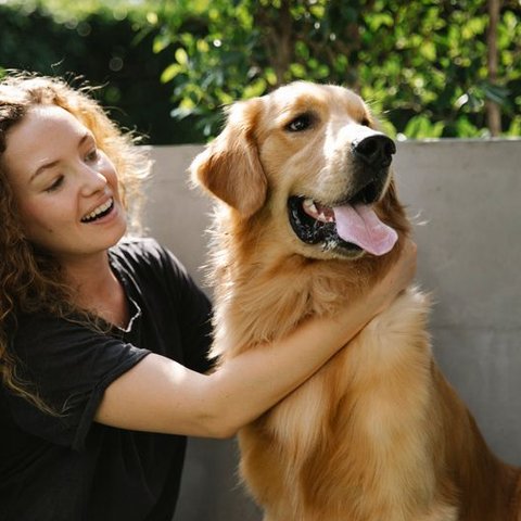 Woman smiling and hugging a golden retriever outdoors