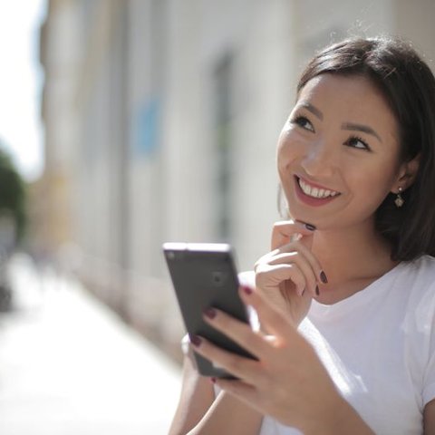 Smiling woman outdoors looking at her smartphone
